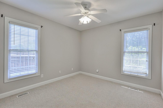 spare room with plenty of natural light, light carpet, and ceiling fan