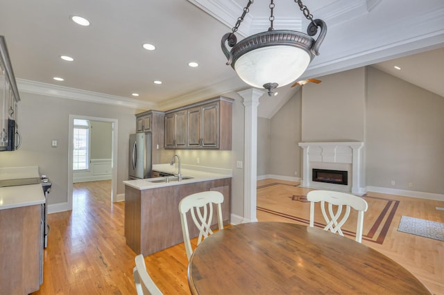 dining space with lofted ceiling, sink, crown molding, a fireplace, and light hardwood / wood-style floors