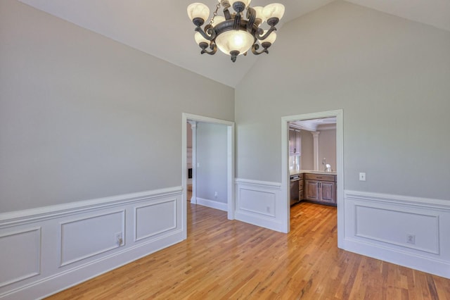 unfurnished room featuring lofted ceiling, light wood-type flooring, and a chandelier