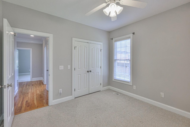 unfurnished bedroom with ceiling fan, a closet, and light carpet