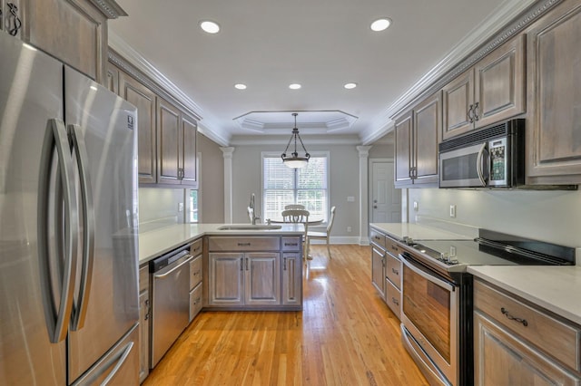 kitchen featuring sink, stainless steel appliances, a tray ceiling, decorative light fixtures, and ornate columns