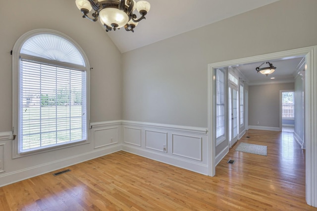 unfurnished room with crown molding, lofted ceiling, a chandelier, and light hardwood / wood-style flooring