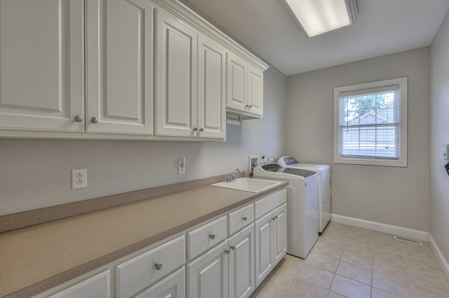 laundry area featuring sink, light tile patterned floors, cabinets, and washing machine and clothes dryer