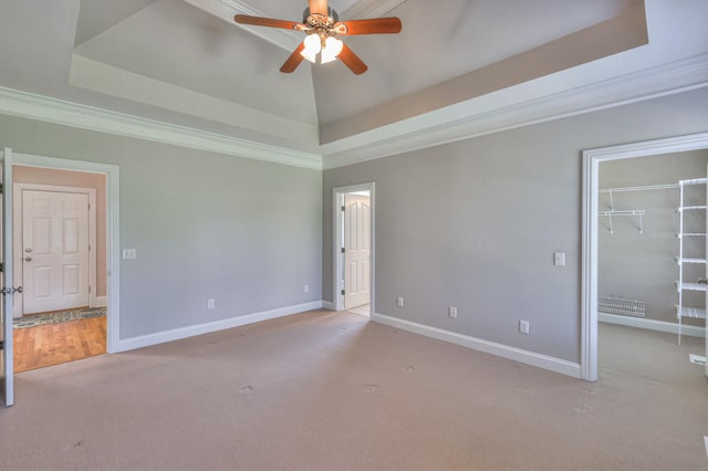 spare room featuring a raised ceiling, crown molding, light colored carpet, and ceiling fan