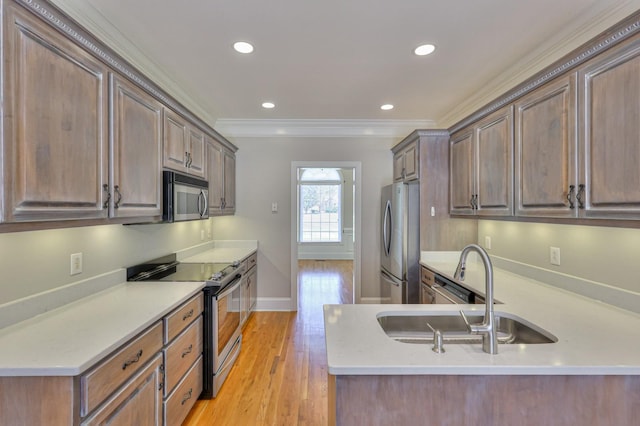 kitchen with sink, ornamental molding, appliances with stainless steel finishes, kitchen peninsula, and light hardwood / wood-style floors