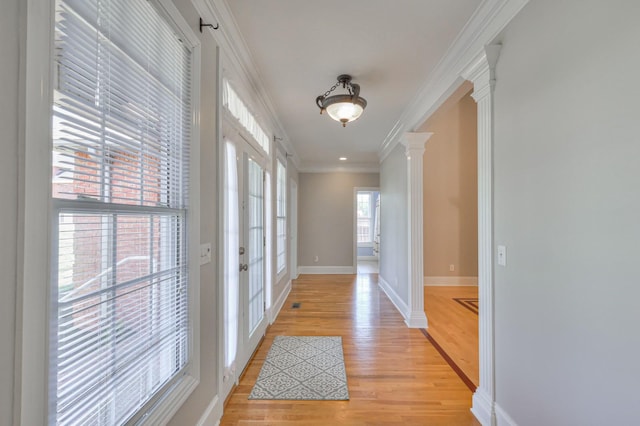 hall featuring crown molding, light hardwood / wood-style floors, and ornate columns