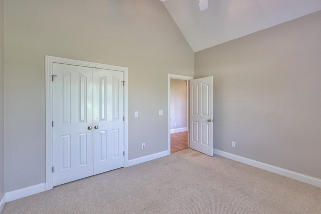 unfurnished bedroom featuring ceiling fan, light carpet, high vaulted ceiling, and a closet