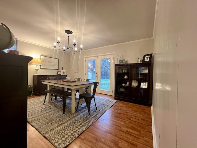 dining space featuring an inviting chandelier, hardwood / wood-style flooring, ornamental molding, and french doors