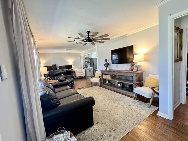 living room featuring wood-type flooring, ornamental molding, and ceiling fan