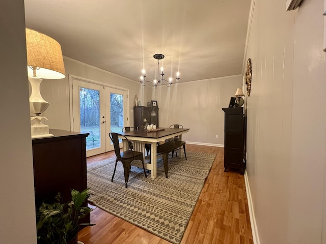 dining room featuring hardwood / wood-style flooring, ornamental molding, an inviting chandelier, and french doors