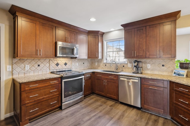 kitchen with sink, light stone counters, dark hardwood / wood-style floors, stainless steel appliances, and decorative backsplash