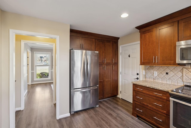 kitchen featuring light stone counters, tasteful backsplash, dark hardwood / wood-style floors, and appliances with stainless steel finishes