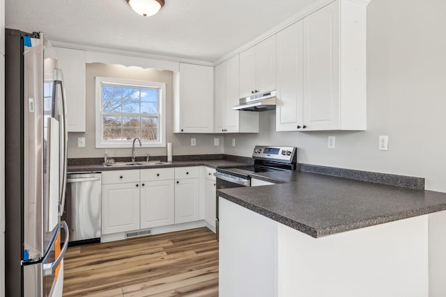 kitchen with visible vents, dark countertops, stainless steel appliances, under cabinet range hood, and a sink