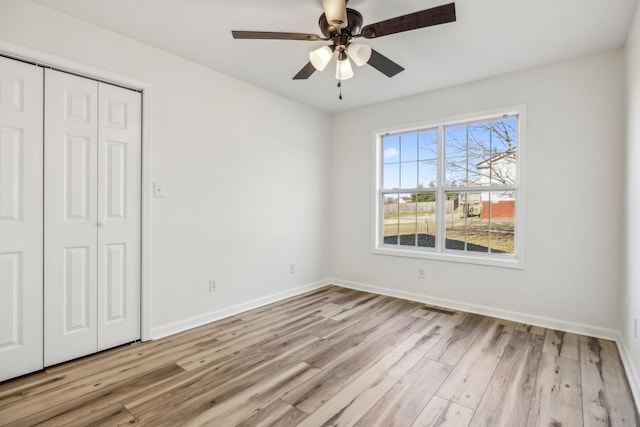 unfurnished bedroom with a closet, visible vents, light wood-style flooring, a ceiling fan, and baseboards