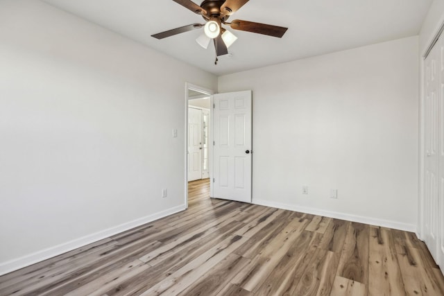 unfurnished bedroom featuring ceiling fan, a closet, wood finished floors, and baseboards