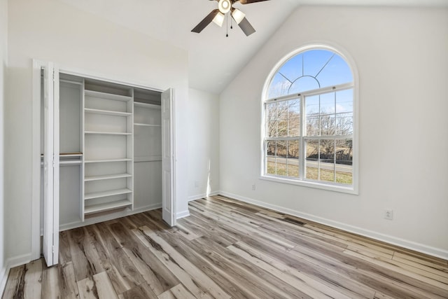 unfurnished bedroom with lofted ceiling, a closet, a ceiling fan, wood finished floors, and baseboards