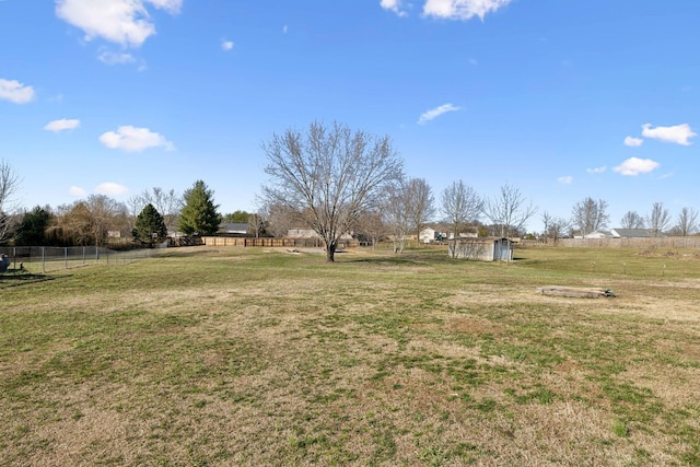 view of yard with a storage shed, fence, an outdoor structure, and a rural view