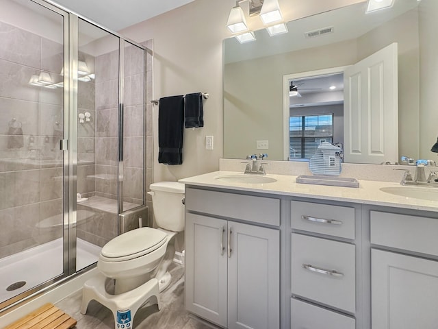 bathroom featuring a shower with door, vanity, and toilet