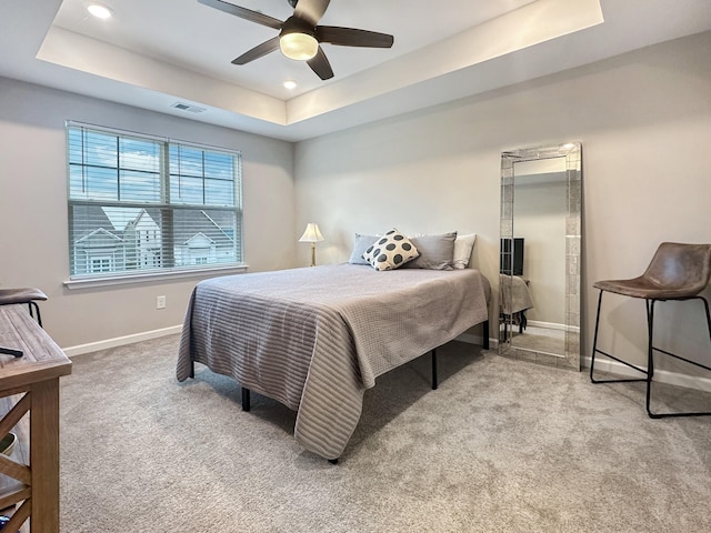 carpeted bedroom with ceiling fan and a tray ceiling