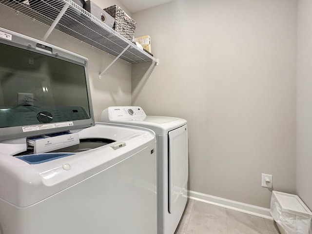 clothes washing area with light tile patterned floors and washer and dryer