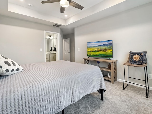 bedroom featuring light carpet, a raised ceiling, ceiling fan, and ensuite bathroom