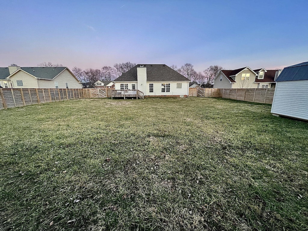 yard at dusk featuring a wooden deck