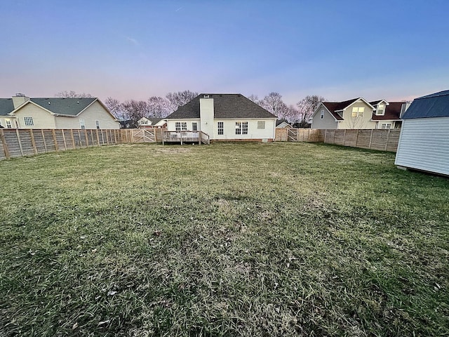 yard at dusk featuring a wooden deck