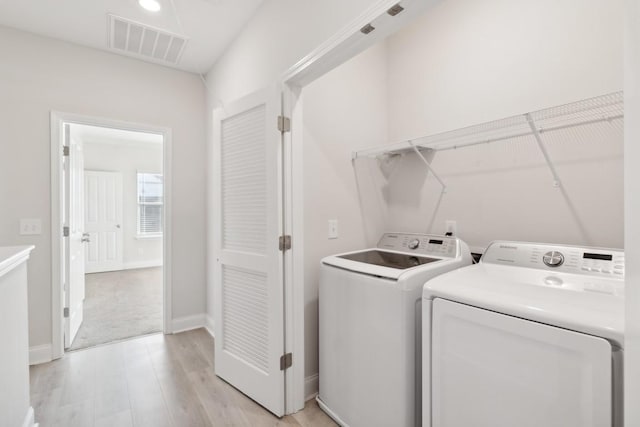 washroom featuring washing machine and dryer and light hardwood / wood-style floors