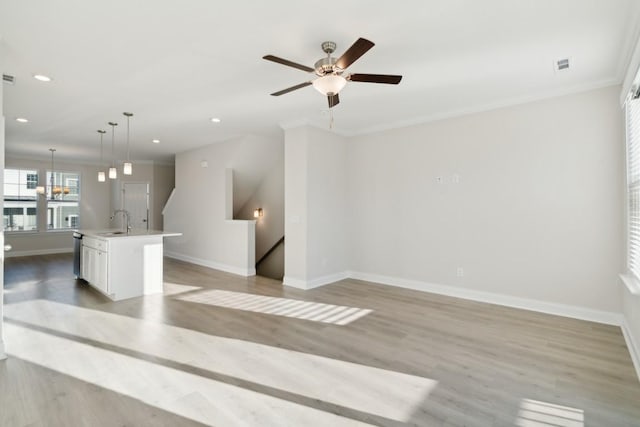 unfurnished living room with ceiling fan, ornamental molding, sink, and light wood-type flooring