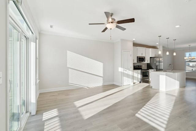 living room featuring ceiling fan with notable chandelier, ornamental molding, light hardwood / wood-style floors, and sink