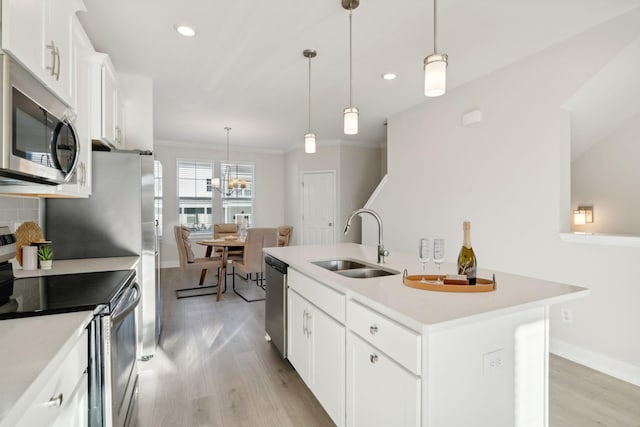 kitchen featuring an island with sink, sink, white cabinets, hanging light fixtures, and stainless steel appliances