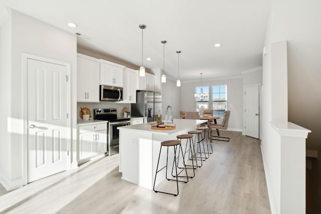 kitchen with sink, white cabinetry, appliances with stainless steel finishes, an island with sink, and pendant lighting