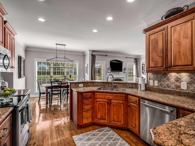 kitchen with sink, crown molding, hanging light fixtures, stainless steel appliances, and backsplash