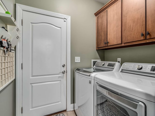 clothes washing area featuring washer and clothes dryer and cabinets