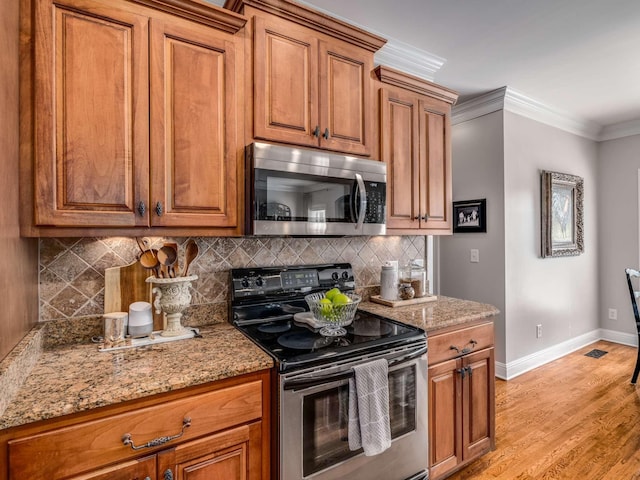 kitchen featuring light stone counters, crown molding, light hardwood / wood-style flooring, stainless steel appliances, and backsplash