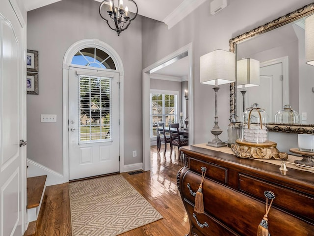 foyer featuring crown molding, an inviting chandelier, and hardwood / wood-style floors