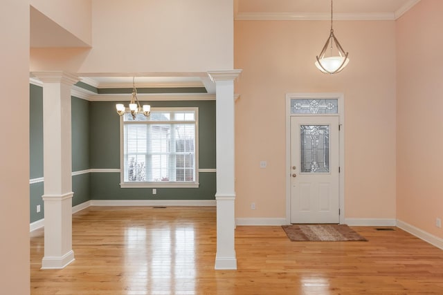 foyer entrance with ornamental molding, decorative columns, and light wood-type flooring