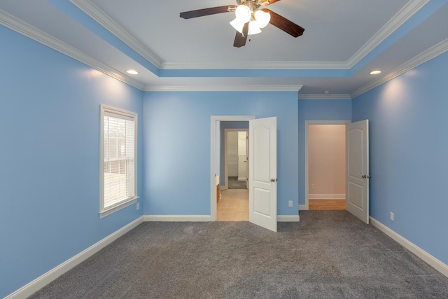 unfurnished bedroom featuring a raised ceiling, crown molding, carpet floors, and ceiling fan