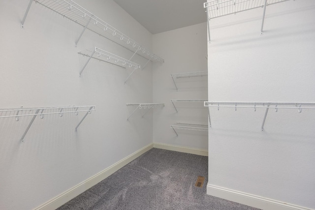 walk in closet featuring dark carpet