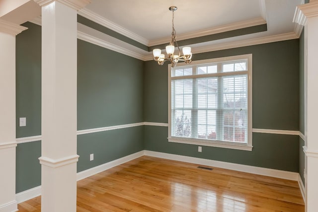 spare room featuring decorative columns, ornamental molding, and light hardwood / wood-style floors