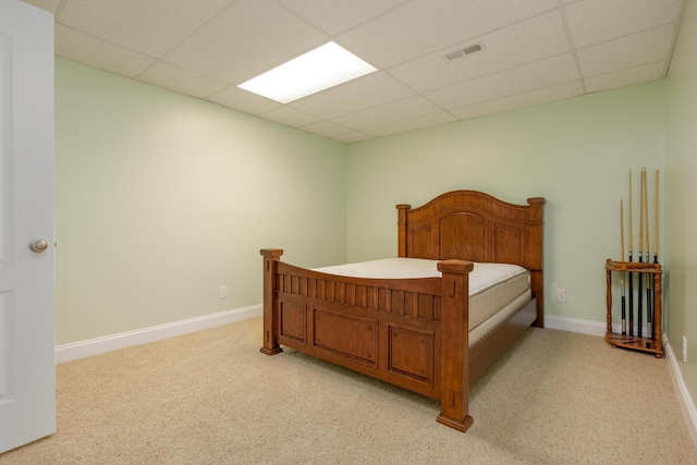 bedroom featuring light carpet and a drop ceiling