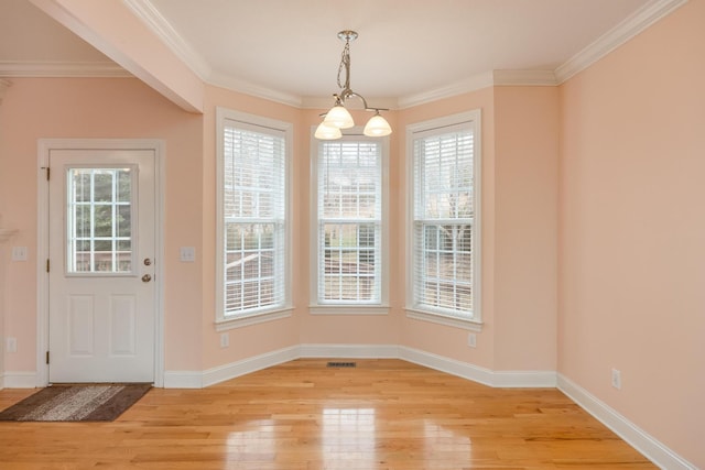 unfurnished dining area featuring ornamental molding and light wood-type flooring