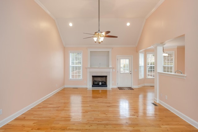 unfurnished living room with lofted ceiling, crown molding, a wealth of natural light, and light hardwood / wood-style flooring