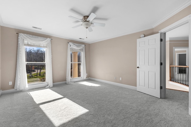 carpeted spare room with visible vents, a ceiling fan, baseboards, and ornamental molding