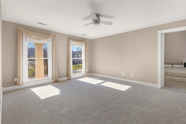 carpeted spare room with visible vents, ceiling fan, baseboards, and ornamental molding