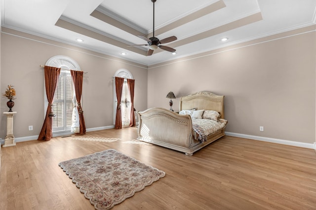 bedroom with light wood finished floors, baseboards, crown molding, and a tray ceiling