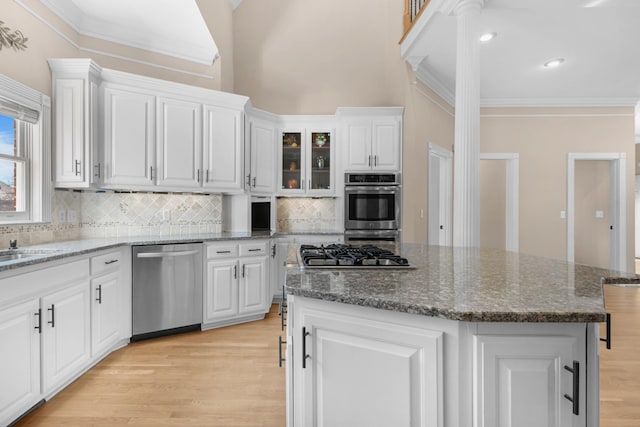 kitchen featuring appliances with stainless steel finishes, white cabinets, a center island, and crown molding