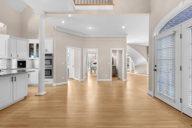 kitchen with white cabinetry, tasteful backsplash, double oven, and ornate columns