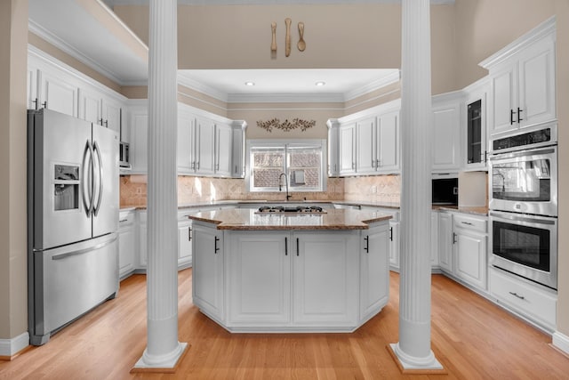 kitchen featuring light stone counters, white cabinets, light wood-style floors, appliances with stainless steel finishes, and a center island