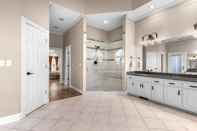 bathroom with tile patterned floors, a shower stall, crown molding, baseboards, and vanity